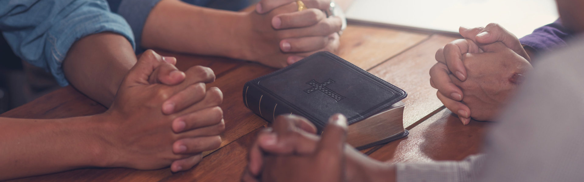 a group of people holding hands with bible